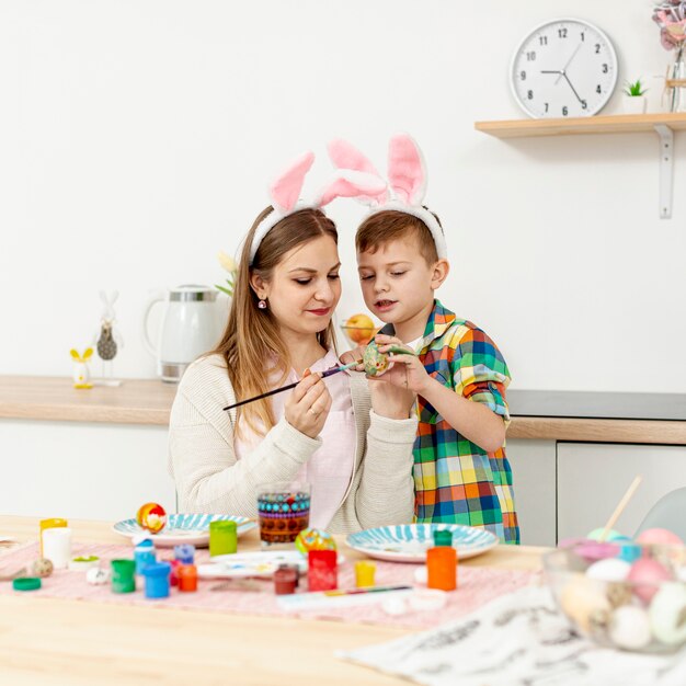 High Angle Mutter und Sohn mit Hasenohren malen Eier