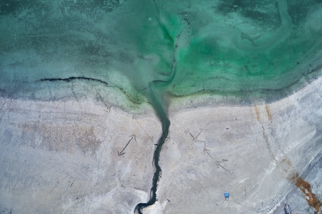 High Angle Shot des türkisfarbenen Wassers des Meeres neben dem Ufer mit Gravuren von Pfeilen