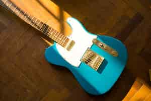 Kostenloses Foto high angle shot einer blauen gitarre auf einer holzoberfläche