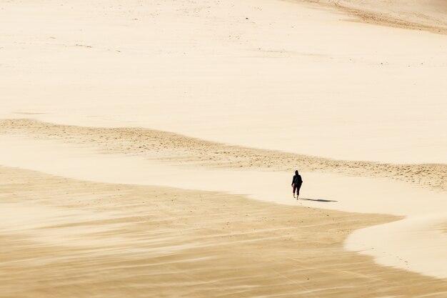 High Angle Shot einer Person, die barfuß auf dem warmen Sand der Wüste geht