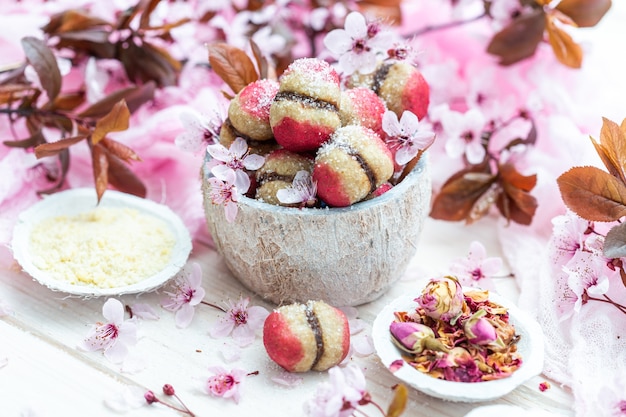 High Angle Shot einer Schüssel mit köstlichen veganen Pfirsichkeksen, umgeben von kleinen Blumen