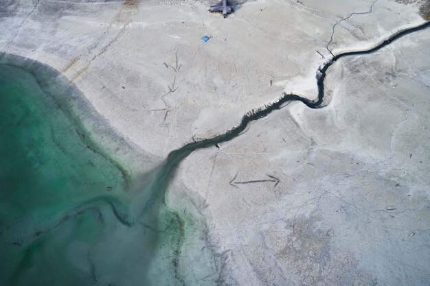 High Angle Shot eines großen Risses am steinigen Ufer neben dem türkisfarbenen Wasser