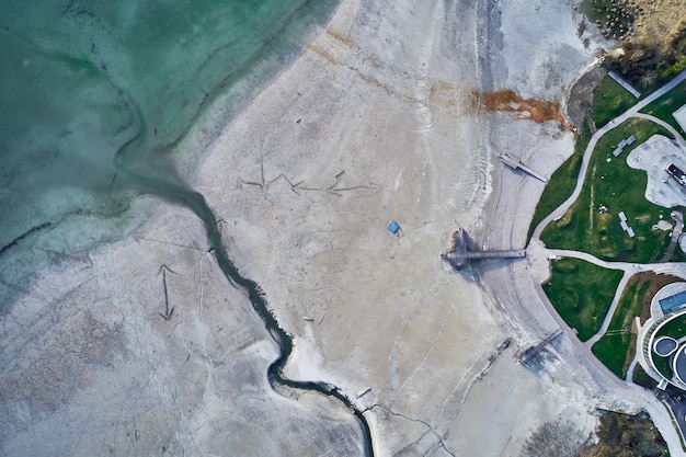 High Angle Shot eines großen Risses am steinigen Ufer neben dem türkisfarbenen Wasser