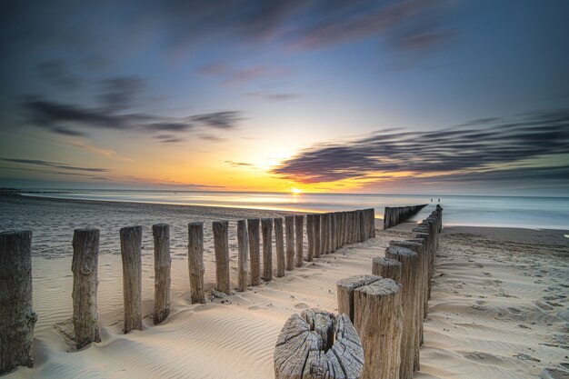 High Angle Shot eines Holzdecks an der Küste, das bei Sonnenuntergang zum Meer führt
