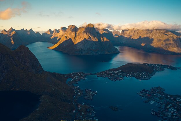 High Angle Shot eines Sees auf einem Gipfel, umgeben von felsigen Bergen, bedeckt mit weißen Wolken