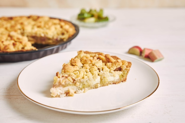 High Angle Shot von einem Stück knuspriger Rhabarbar-Torten-Torte mit einigen Zutaten auf einem Tisch