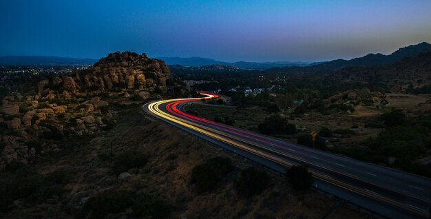 High Angle Shot von gelben und roten Lichtern auf der Autobahn, die nachts von Felsen umgeben ist