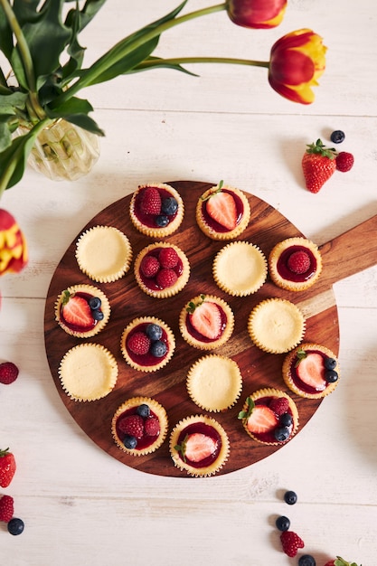 High angle shot von käse cupcakes mit fruchtgelee und früchten auf einem holzteller Kostenlose Fotos