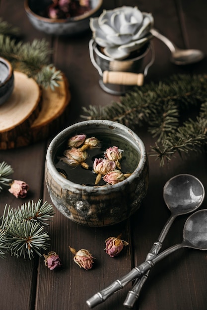 High Angle Tee mit getrockneten Blumen in rustikaler Tasse mit Teelöffeln