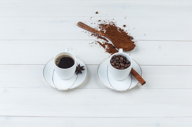 High Angle View-Kaffee in der Tasse mit gemahlenem Kaffee, Gewürzen, Kaffeebohnen auf hölzernem Hintergrund. horizontal