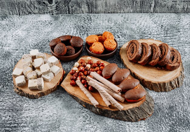 High Angle View Tee mit Waffeln und Kuchen auf Tellern und Schneidebrett auf leicht strukturiert