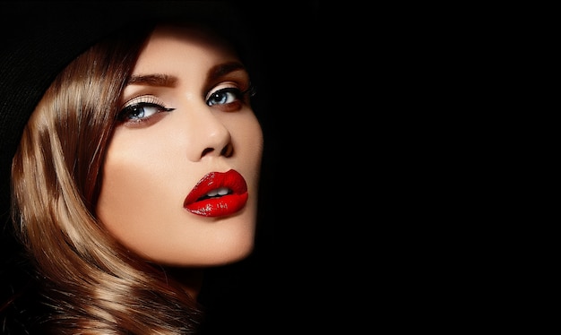 High Fashion Look.glamour Nahaufnahme Porträt des schönen sexy stilvollen kaukasischen jungen Frau Modell mit hellem Make-up, mit roten Lippen, mit perfekter sauberer Haut in großen schwarzen Hut