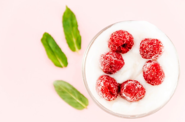 Himbeeren mit Sahne und grünen Blättern