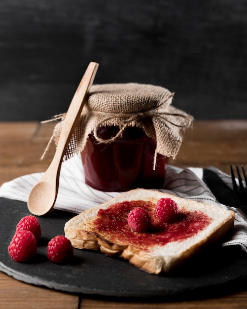 Himbeermarmelade auf Brot mit Glas und Löffel