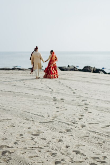 Hindisches Hochzeitspaar geht entlang dem Ozeanufer