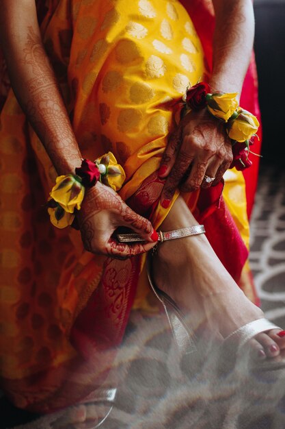 Hindu-Braut setzt traditionelles Armband auf ihr Bein