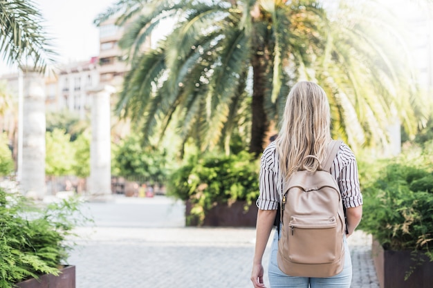 Hintere Ansicht der blonden jungen Frau mit ihrem Rucksack