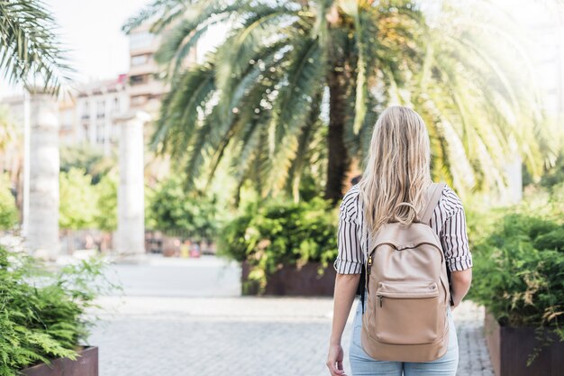 Hintere Ansicht der blonden jungen Frau mit ihrem Rucksack