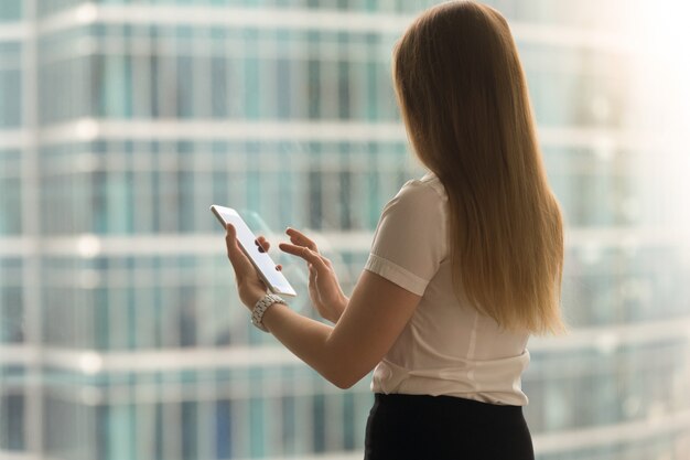 Hintere Ansicht der Frau streichen mit dem Finger auf Tablettenschirm