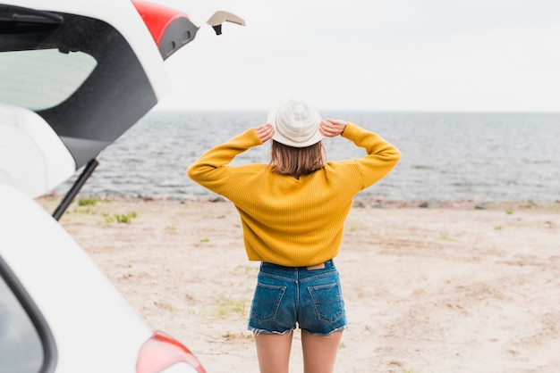 Hintere Ansicht der reizenden Frau das Meer gegenüberstellend