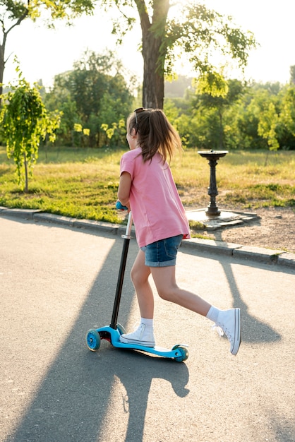 Hintere Ansicht des Mädchens mit rosa T-Shirt auf Roller