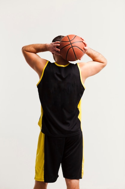Hintere Ansicht des männlichen Spielers Basketball nah an Kopf halten