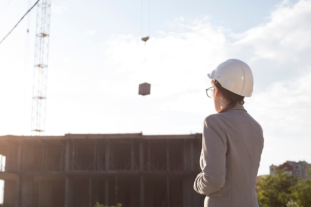 Hintere Ansicht des tragenden Hirschhutes des weiblichen Architekten, der Baustelle betrachtet