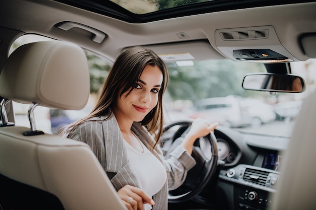 Hintere Ansicht einer attraktiven jungen Geschäftsfrau, die über ihre Schulter schaut, während sie ein Auto fährt