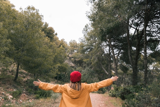 Kostenloses Foto hintere ansicht einer jungen frau, die heraus seine hand im wald ausdehnt