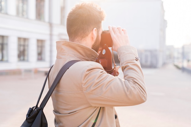 Hintere Ansicht eines männlichen Reisenden, der das Foto in der Stadt mit Kamera macht