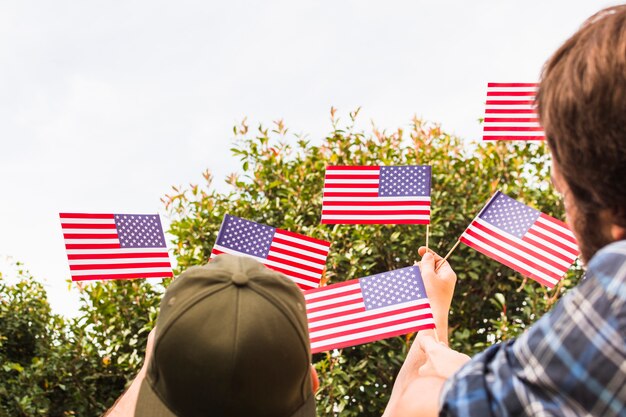 Hintere Ansicht von Zwei-mann, der in der Hand kleine USA-Flaggen hält
