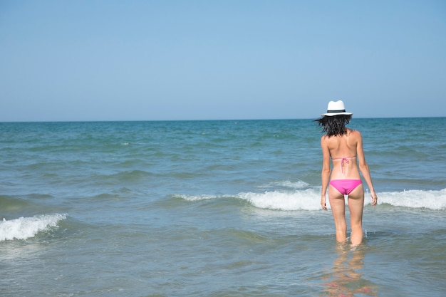 Hintere Ansichtfrau, die im Wasser am Strand steht