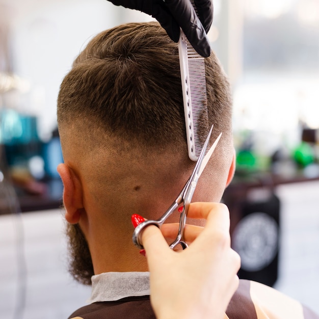 Hintere Ansichtfrau, welche die Haarnahaufnahme ihres Kunden schneidet