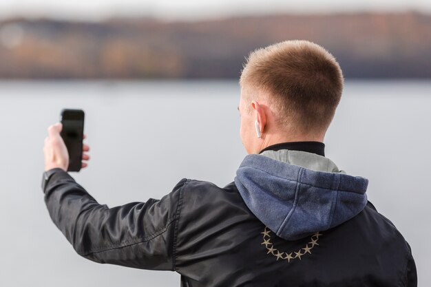 Hinterer Ansichtmann, der ein selfie beim Hören Musik in den Ohrhörern nimmt