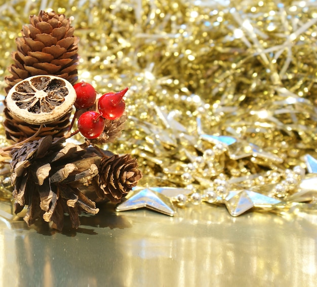 Hintergrund Weihnachten mit Tannenzapfen und Beeren auf einem goldenen Hintergrund