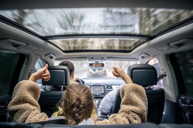 Hintergrundbild von einem kleinen Mädchen, das während einer Familienfahrt auf dem Rücksitz eines Autos sitzt