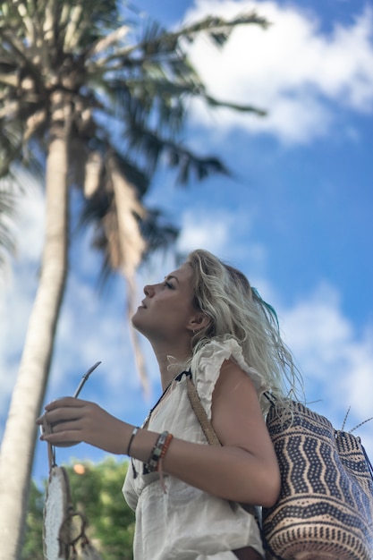 Hippiemädchen mit langen blonden Haaren in einem Kleid auf dem Dach.