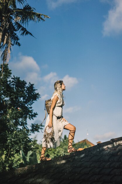 Hippiemädchen mit langen blonden Haaren in einem Kleid auf dem Dach.