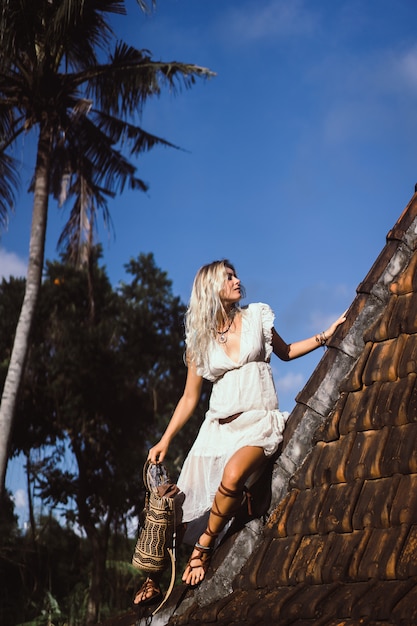 Hippiemädchen mit langen blonden Haaren in einem Kleid auf dem Dach.