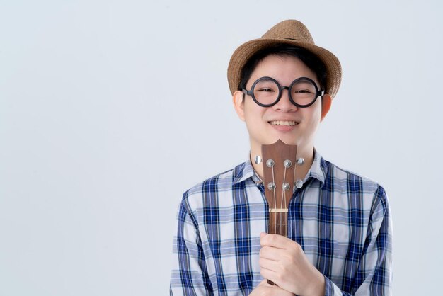 Hipster asiatischer Mann Hand halten Ukulele mit Lächeln glücklich Moment Reisekostüm Porträt