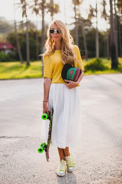 Hipster coole Frau mit Skateboard und Mütze posierend lächelnd im Urlaub
