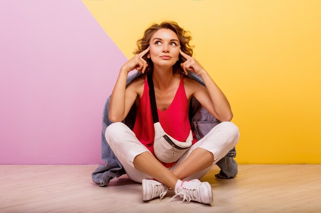 Hipster Frau mit Überraschungsgesicht, das im Studio auf rosa und gelb aufwirft.