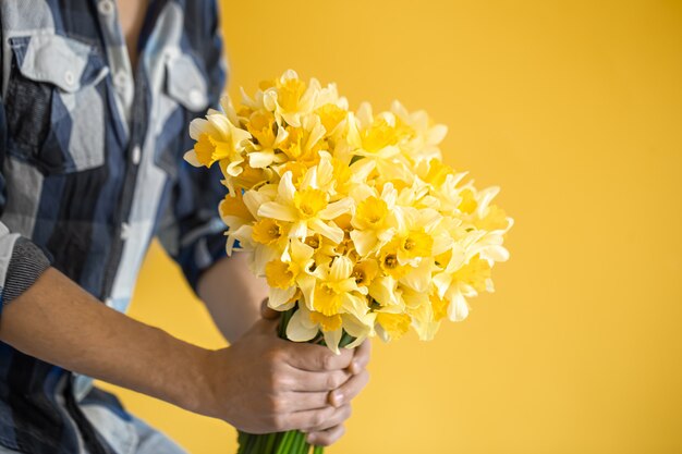 Hipster Mann auf einem gelben Hintergrund in einem Hemd und einem Blumenstrauß.