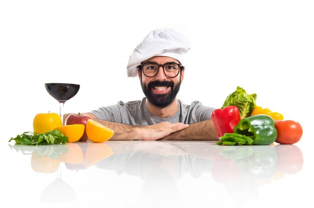 Hipsterkoch mit mehreren Gemüse und Früchten auf dem Tisch