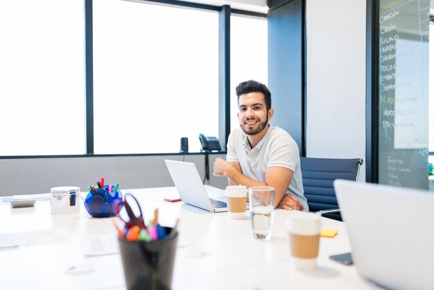 Hispanische Führungskraft mit Laptop während der Arbeit im Büro