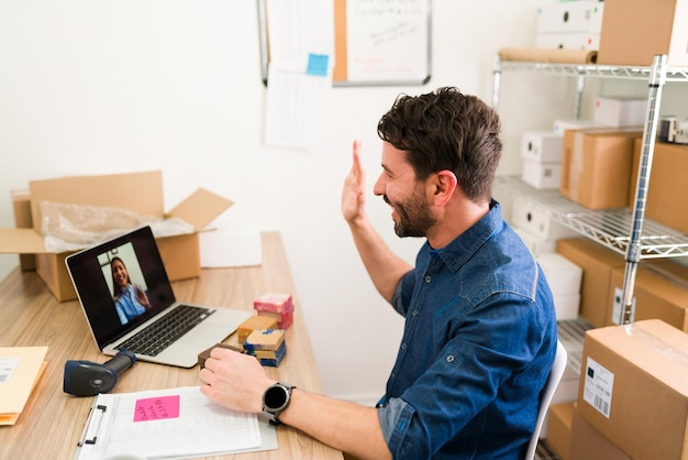 Hispanischer Geschäftsinhaber begrüßt seinen Anbieter bei einem Online-Videoanruf. Glücklicher Unternehmer, der versucht, hausgemachte Seife zu verkaufen und ein Startup zu leiten