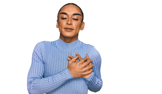 Kostenloses Foto hispanischer transgender-mann mit make-up und langen haaren in lässiger kleidung, lächelnd mit den händen auf der brust, geschlossenen augen und dankbarer geste im gesicht, gesundheitskonzept
