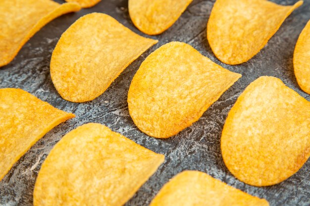 Hochauflösendes Foto von knusprig gebackenen fünf Chips, die in Reihen auf grauem Tisch aufgereiht sind