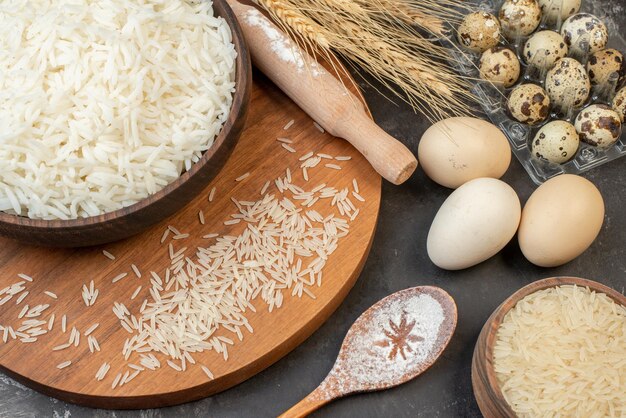 Hochauflösendes Foto von perfektem Langreis in braunen Töpfen und auf Holzbretteiern auf grauem Hintergrund