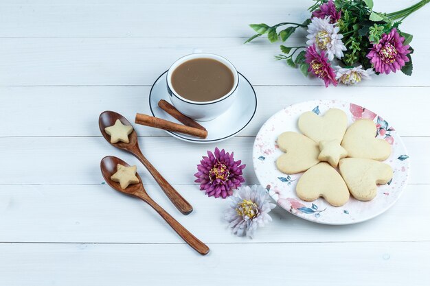 Hochwinkelansicht herzförmig und Sternplätzchen im weißen Teller mit Blumen